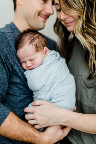 New parents holding their newborn son during a lifestyle newborn session in Richmond, Virginia.