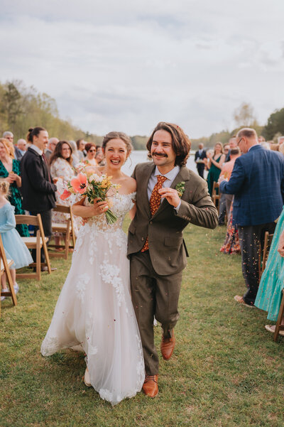 Newlyweds smile as they walk down the aisle