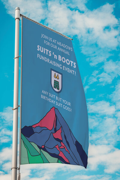A windflag with the stained glass style Mt.Hood artwork created by Ayanna Richilano Designs promoting the suits 'n boots event at Mt.Hood Meadows