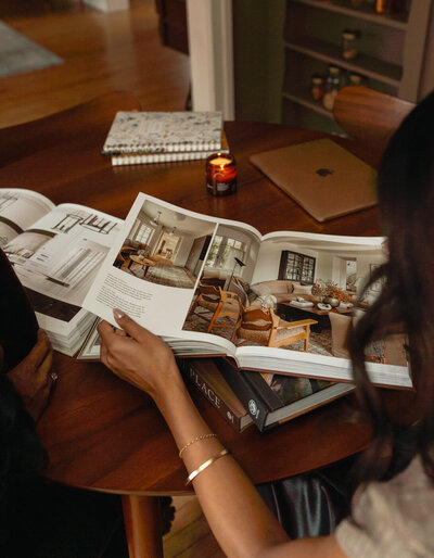 hands flipping through a design book with candles on the table 