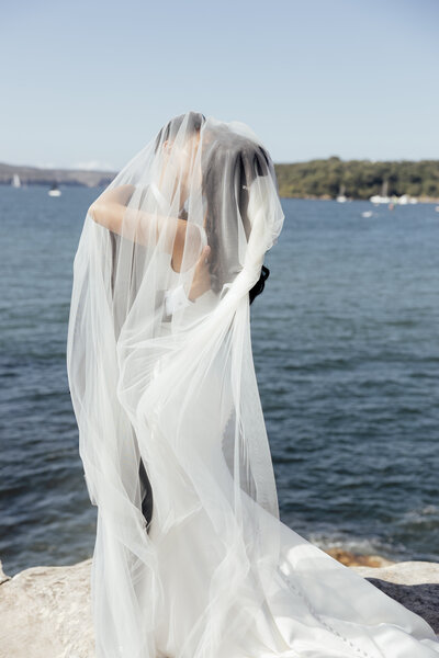 balmoral beach wedding couple having a kiss under the brides veil flowing in the sind