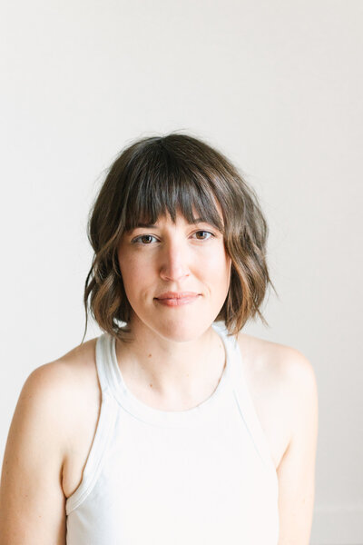A professional headshot of a woman with a short haircut with bangs