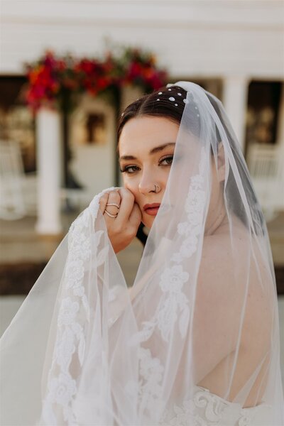Bride holds her veil in front of white chapel at Chapel Creek in Denton.