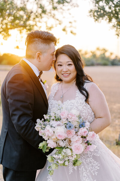 a bride and groom pose while the bride's veil blows around them at their Sacramento wedding.