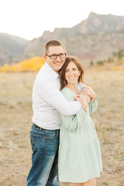 husband and wife hug at Flatirons in Boulder, Colorado