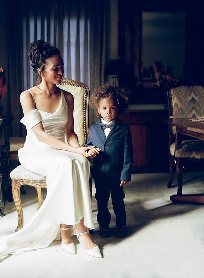 California Bride in a white gown smiling and posing with her young nephew, capturing a heartfelt wedding day moment.

