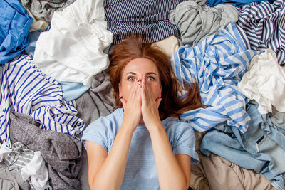 woman surrounded by clothes decluttering