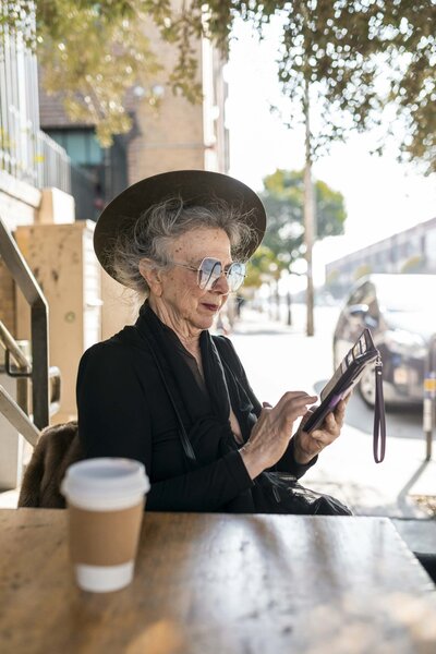 Senior woman in black clothes sitting at a cafe