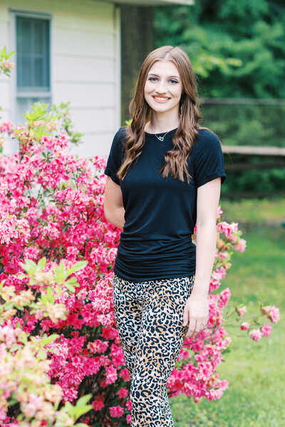 High school senior standing in front of pink flowers