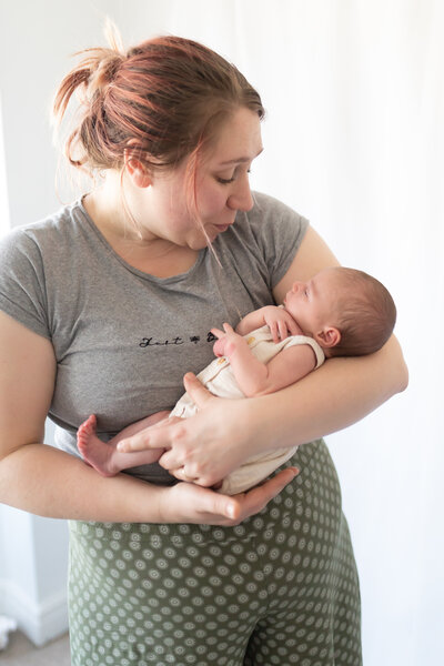 female photographer shhing a newborn baby in her arms in a studio