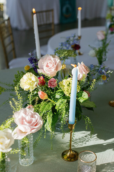 Spring wedding flowers with blue and pink taper candles and colored linens