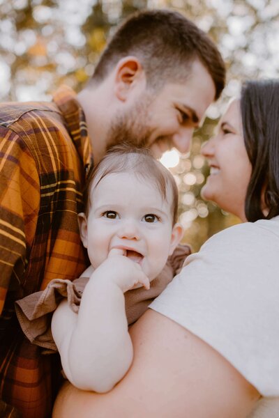 Family of five sitting on a blanket in  a field.