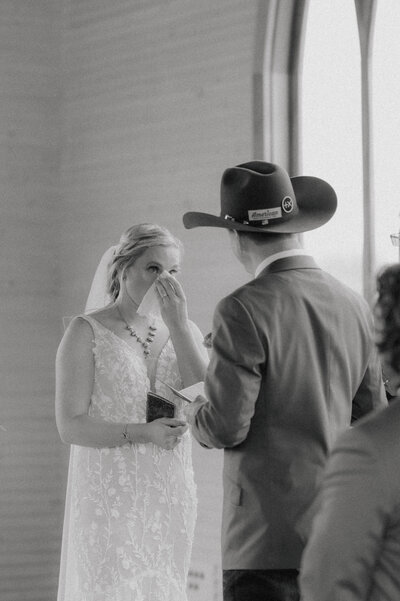 bride wipes a tear as groom reads her his vows