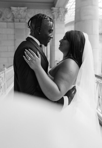 The bride and the groom are hugging and looking at each other at the City Hall