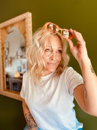Brandy boyett holding orange sunglasses above her head