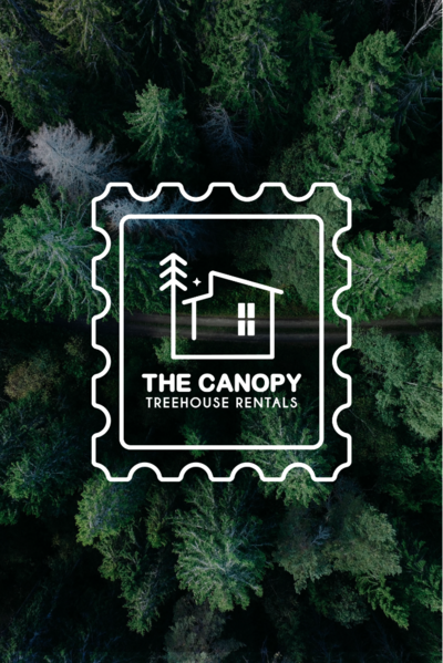 Birds eye view of a forest canopy with a white logo that looks like a stamp with a cabin in the center that reads "The Canopy Treehouse Rentals"