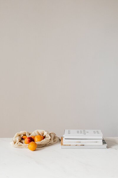 white books stacked on a table with oranges