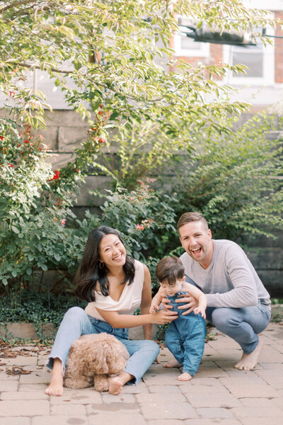 Mom and dad smile with young son on outdoor patio