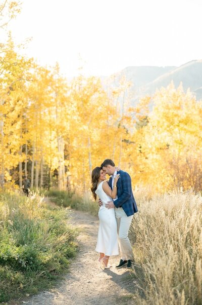 Couple stands together with bright yellow aspens during fall at their Snowmass engagement session. 