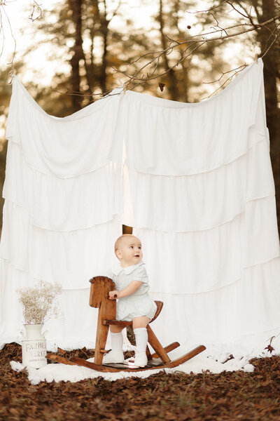 Baby boy birthday photos in heirloom bubble with wooden rocking horse by Lawrenceville Baby Photographer