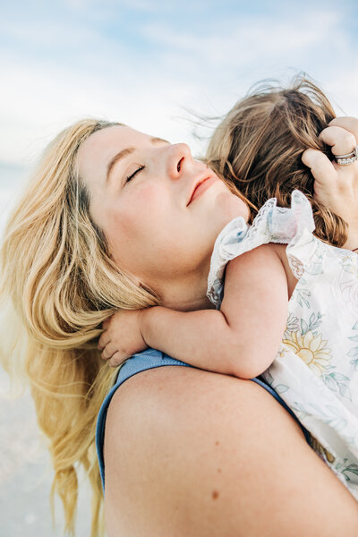Mother and little girl cuddle on the beach in st. pete