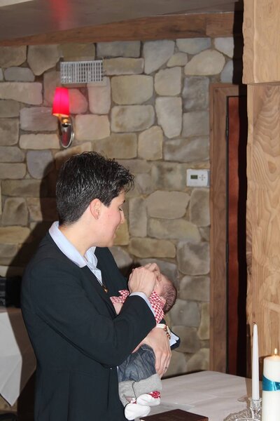 Rev-Chani-holds-baby-and-touches-head-of-baby-during-ceremony