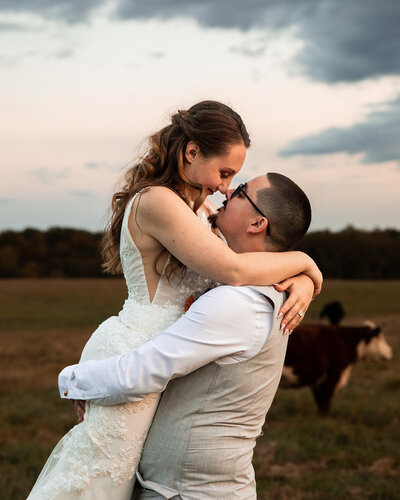 Bride and groom smiling in a cow pasture
