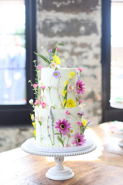 Wedding cake with bright spring flowers at Rose Hill Event Center