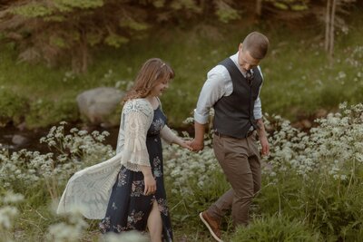 groom leads bride through a field of wildflowers