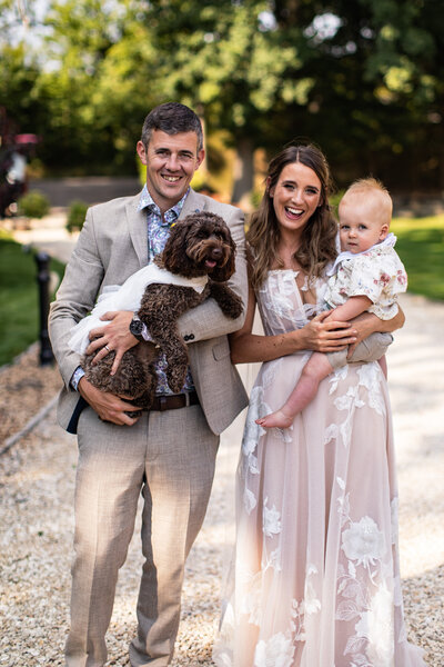 bride and groom posing with dog and baby