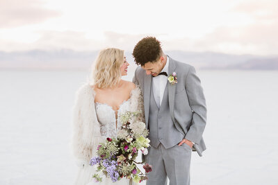 A bride and groom laugh while enjoying the bonneville salt flats near Utah. 