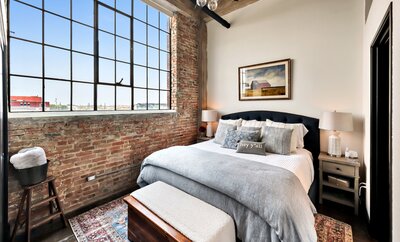 Bedroom with exposed brick  in this 3-bedroom, 2-bathroom luxury condo in downtown Waco, TX