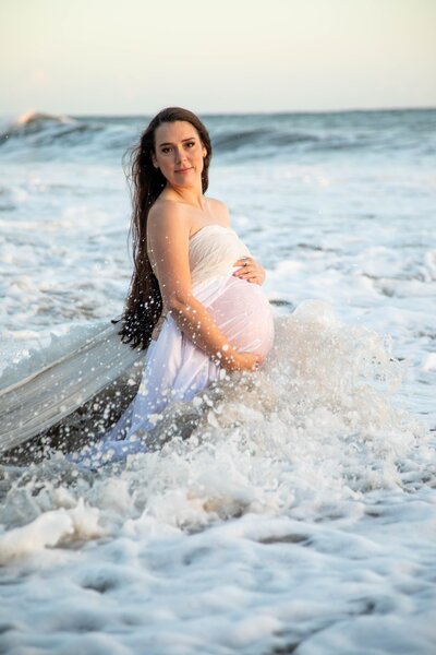 Woman standing in ocean holding pregnant belly | California Maternity Session