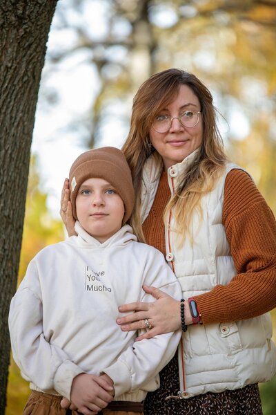 Mother standing outside with her son in front of a tree