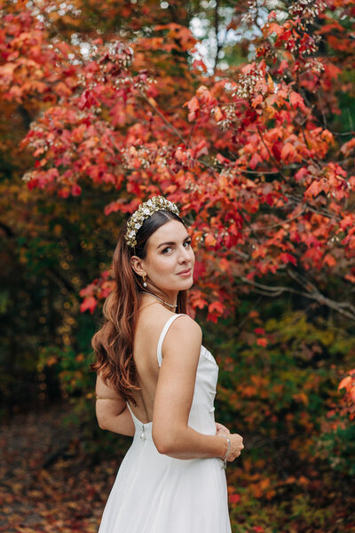 Bride looking at camera with red leaves behind her