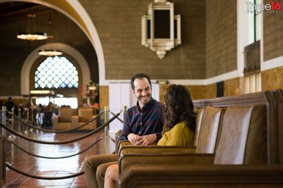 Groom to be smiles at his fiance while sitting in the lobby of the Los Angeles Union Station