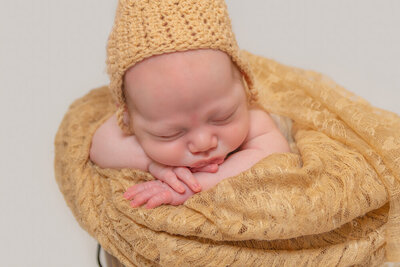 posed newborn baby in a bucket wearing a bonnet - Townsville Newborn Photography by Jamie Simmons