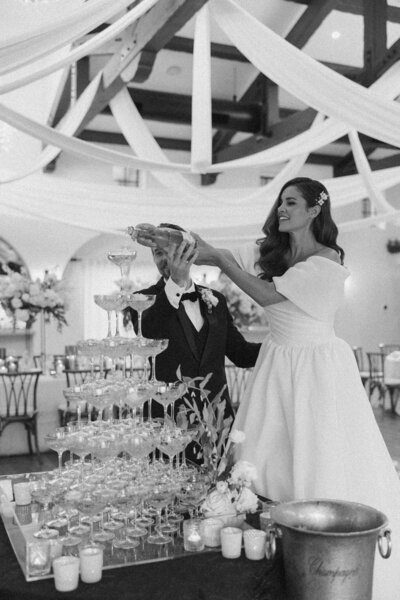 Bride sitting and groom standing next to her outside at table
