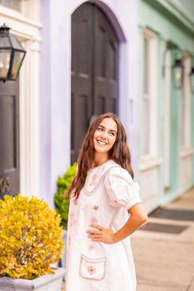 High school senior posing at Rainbow Row, Charleston, SC, in light-filled, authentic portraits