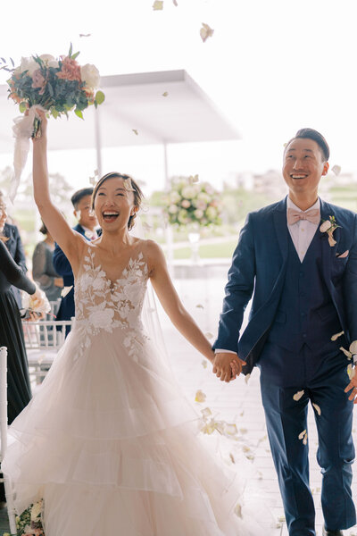 Bride and groom walking down aisle with guests tossing petals