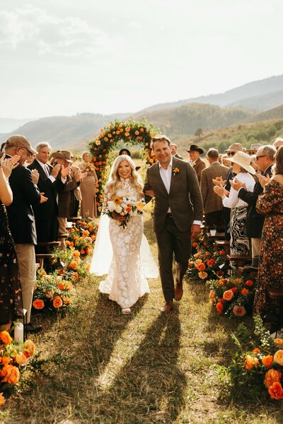 photo of man and woman embracing in a field with mountains in the distance taken by Luxury wedding photographer Jackson Hole