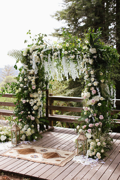 Luscious green wedding arch with hundreds of roses and white cascading flowers