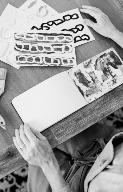 Black and White sketchbook photo of artist reviewing paintings