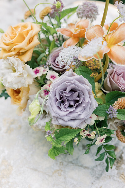 White blush and peach flowers in gold compote at outdoor wedding