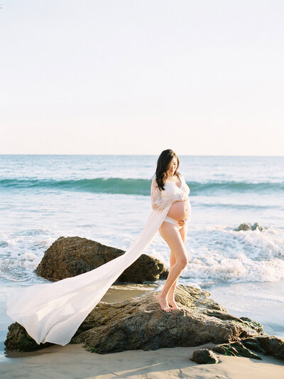 Expectant mother in a pink dress holds her belly during her maternity portrait session