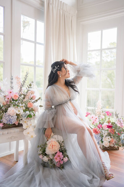 girl in lace tulle blue robe by french windows at kwila lodge having maternity photos taken