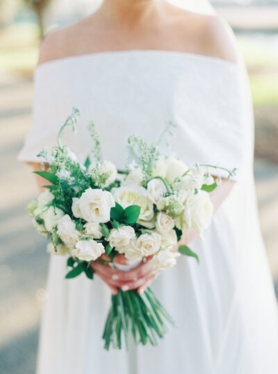 White shoes with bows on the toe surrounded by white flowers