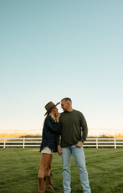 A mom and dad are carrying their baby up a road with a snowy forest behind them.