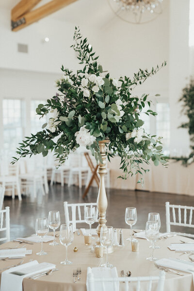 Greenery centerpiece on table at white and gold styled reception