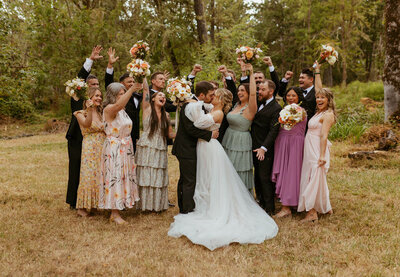 The wedding party cheers for the couple during their photso